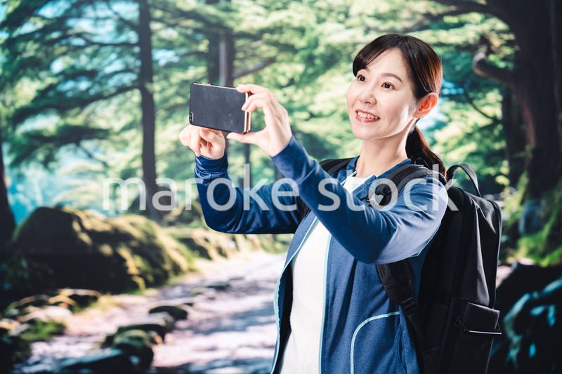 ハイキングをしながらスマホで写真を撮る若い女性