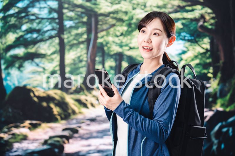 ハイキングをしながらスマホで写真を撮る若い女性