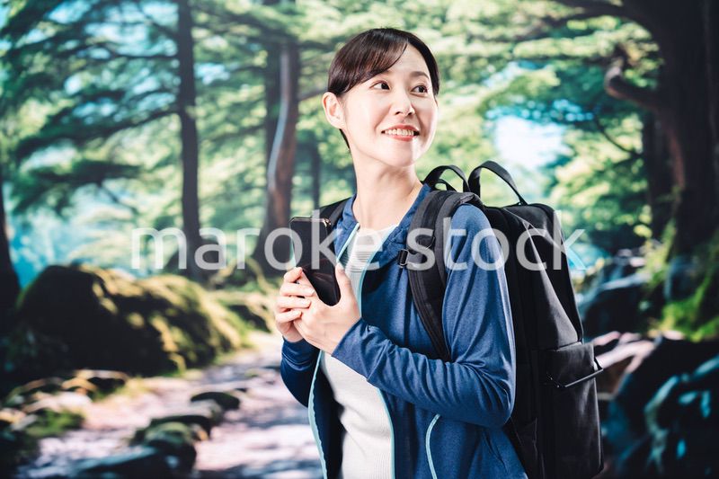 ハイキングをしながらスマホで写真を撮る若い女性