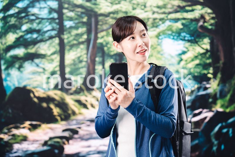 ハイキングをしながらスマホで写真を撮る若い女性