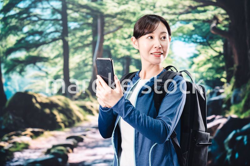 ハイキングをしながらスマホで写真を撮る若い女性