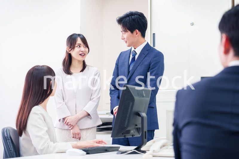 職場で上司に結婚の報告をするビジネスパーソンのカップル