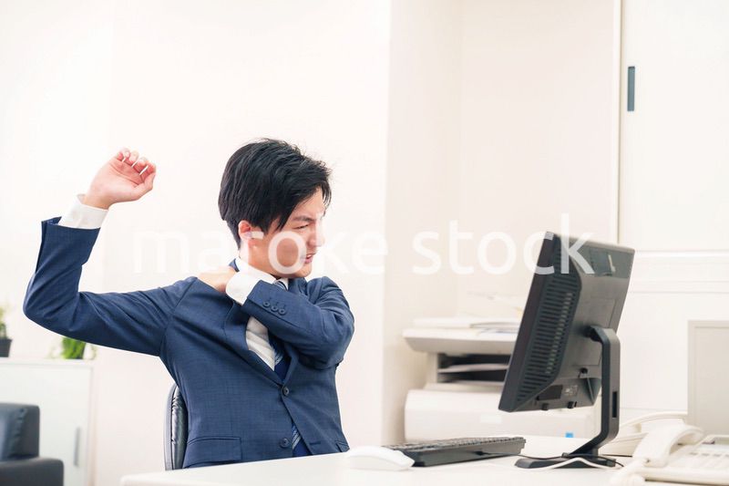 オフィスで肩こりに悩むビジネスマン