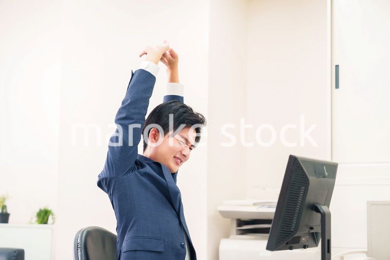 オフィスで肩こりに悩むビジネスマン