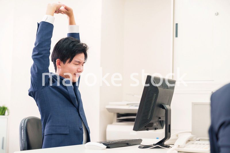オフィスで肩こりに悩むビジネスマン