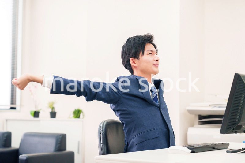 オフィスで肩こりに悩むビジネスマン