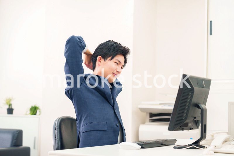 オフィスで肩こりに悩むビジネスマン