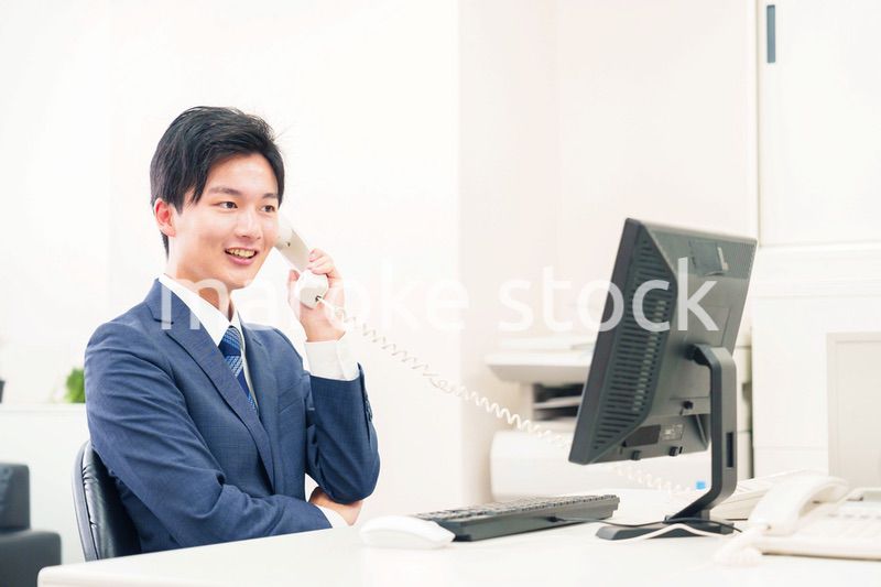 オフィスの電話で話すビジネスマン