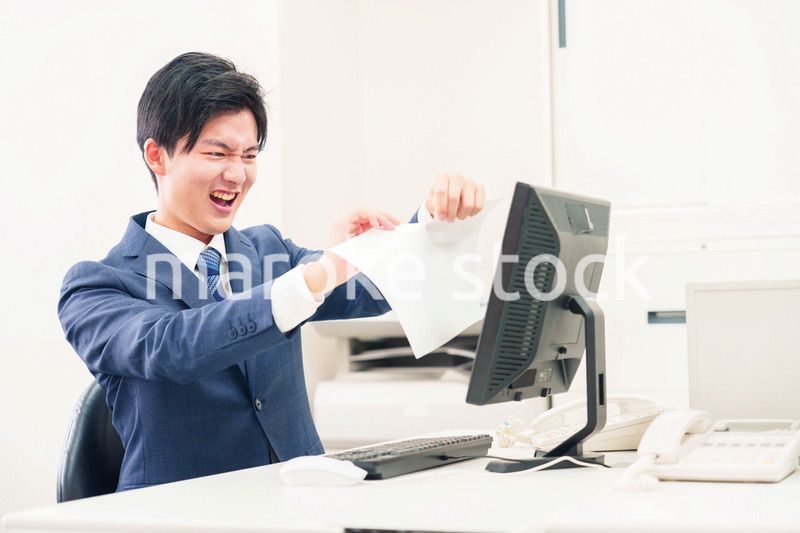 オフィスで書類を破り捨てるビジネスマン