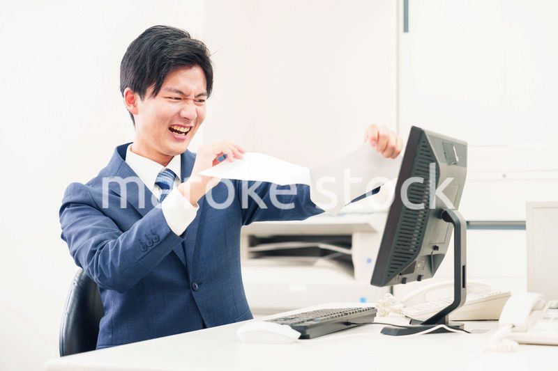 オフィスで書類を破り捨てるビジネスマン