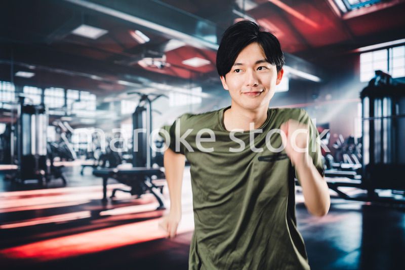 スポーツジムでランニングをする若い男性