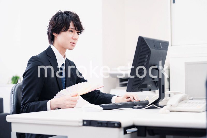 扇子で扇ぎながら仕事をするビジネスマン