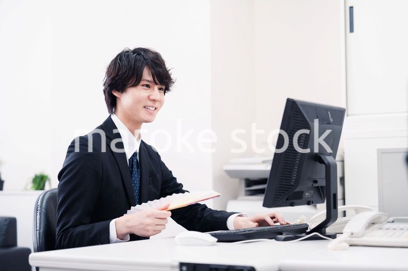 扇子で扇ぎながら仕事をするビジネスマン