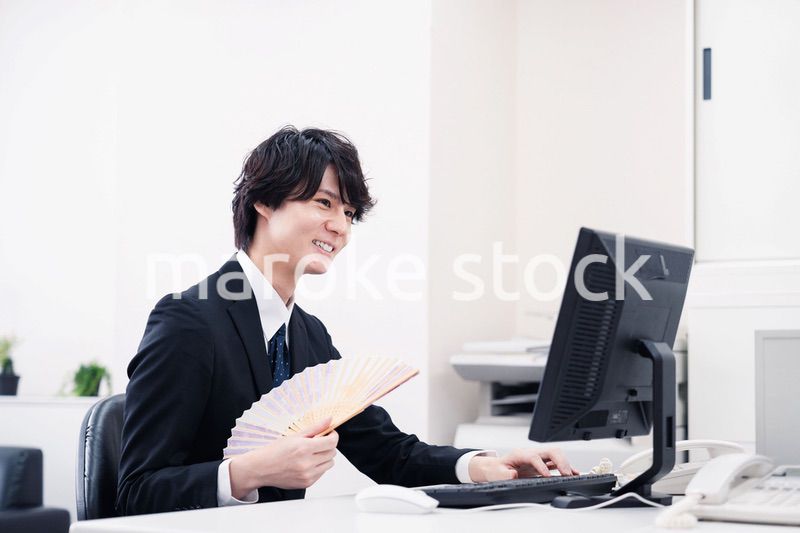 扇子で扇ぎながら仕事をするビジネスマン