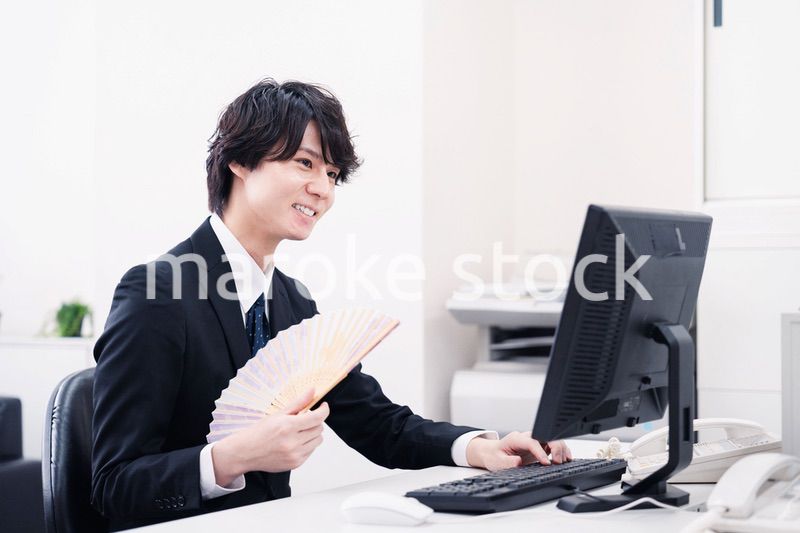 扇子で扇ぎながら仕事をするビジネスマン