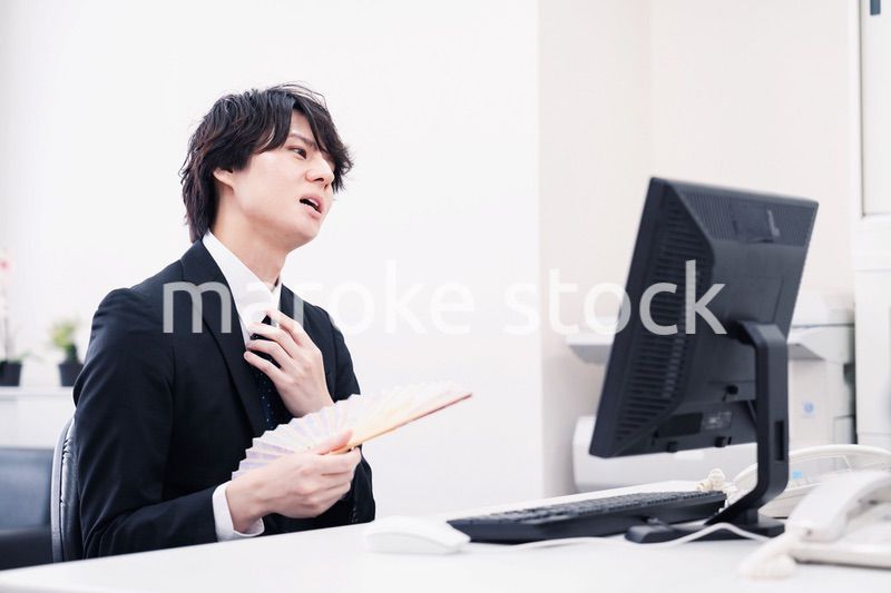 扇子で扇ぎながら仕事をするビジネスマン