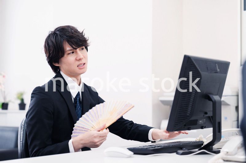 扇子で扇ぎながら仕事をするビジネスマン