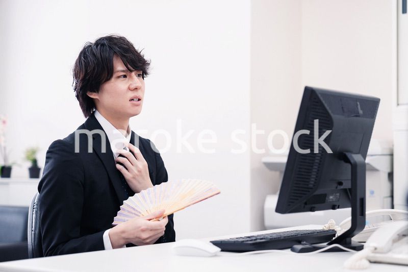 扇子で扇ぎながら仕事をするビジネスマン