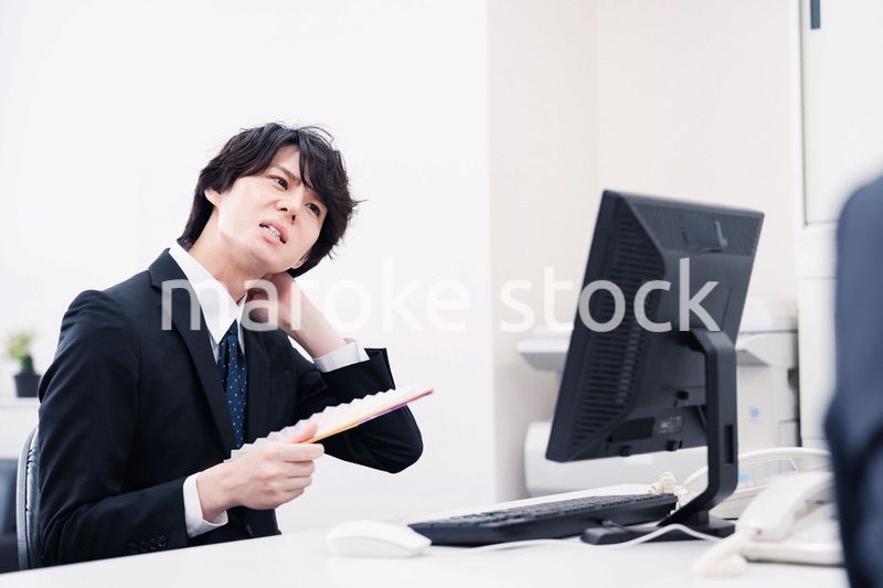 扇子で扇ぎながら仕事をするビジネスマン