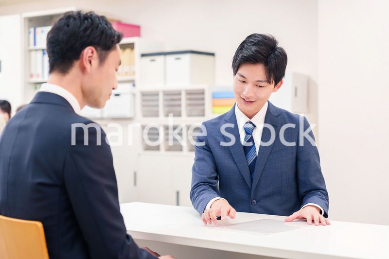 窓口で来客の対応をするビジネスマン