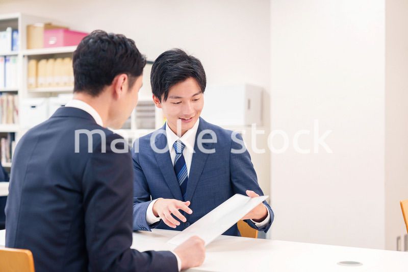 窓口で来客の対応をするビジネスマン