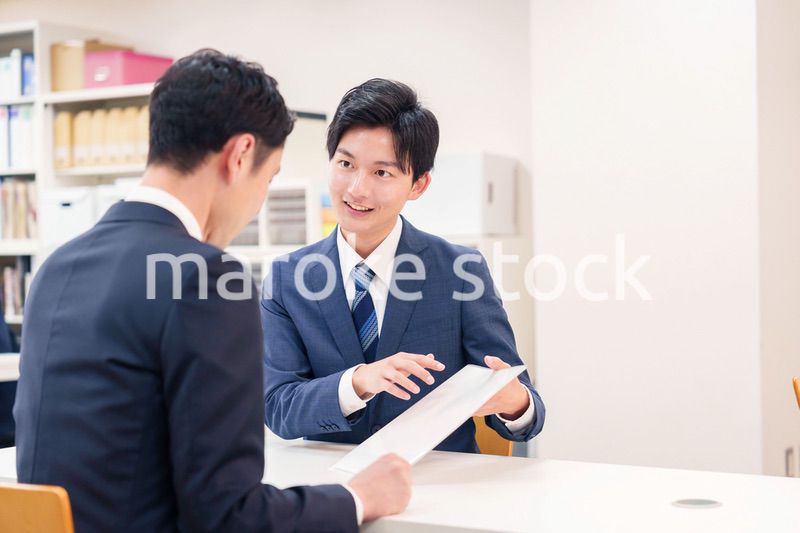 窓口で来客の対応をするビジネスマン