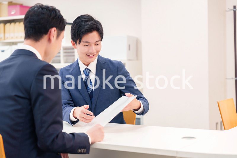 窓口で来客の対応をするビジネスマン