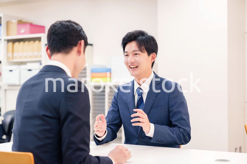 窓口で来客の対応をするビジネスマン