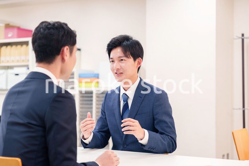 窓口で来客の対応をするビジネスマン