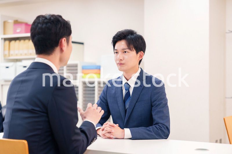 窓口で来客の対応をするビジネスマン