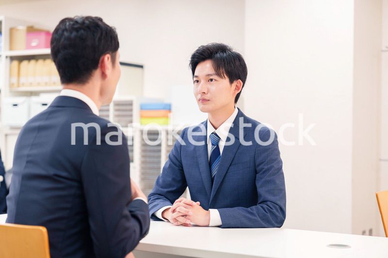 窓口で来客の対応をするビジネスマン