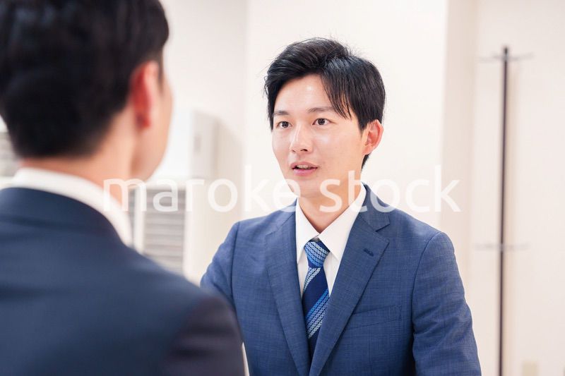 窓口で来客の対応をするビジネスマン