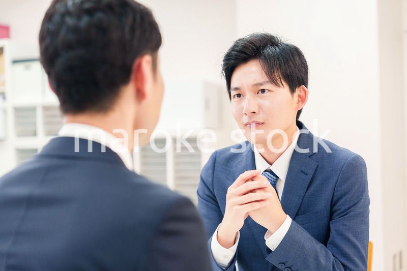 窓口で来客の対応をするビジネスマン