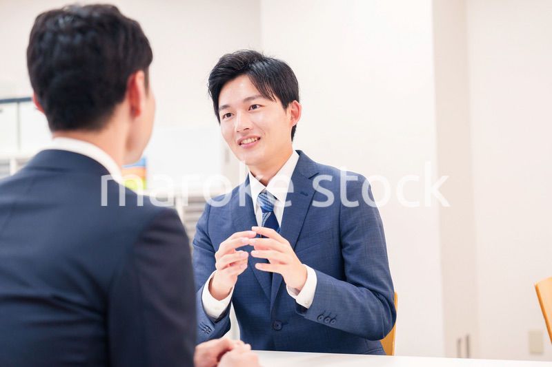 窓口で来客の対応をするビジネスマン