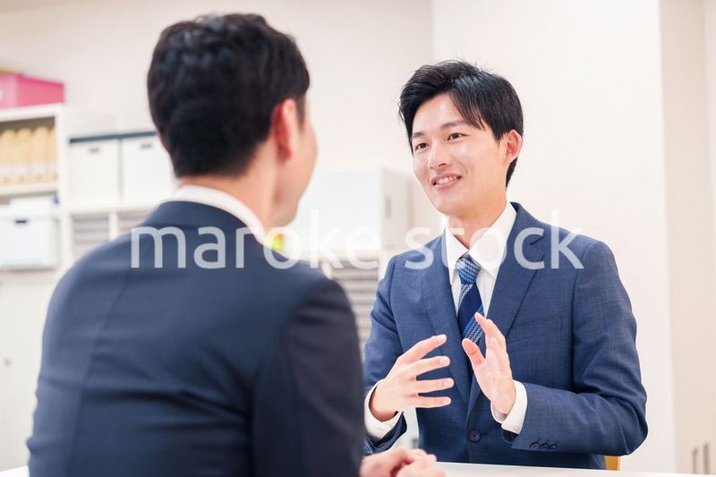 窓口で来客の対応をするビジネスマン