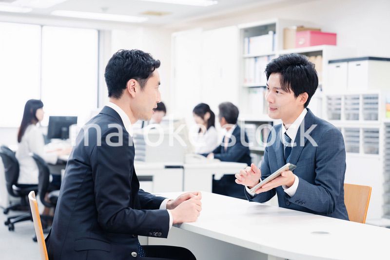 窓口でタブレットを用いて案内をする男性スタッフ