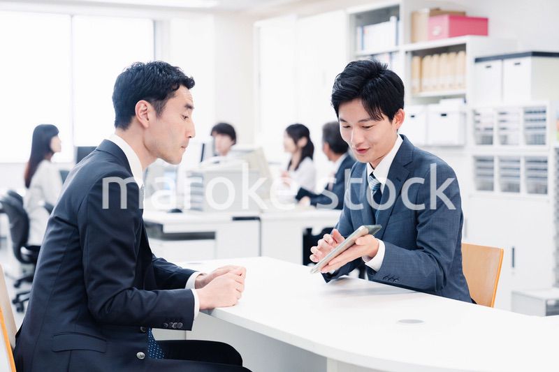 窓口でタブレットを用いて案内をする男性スタッフ