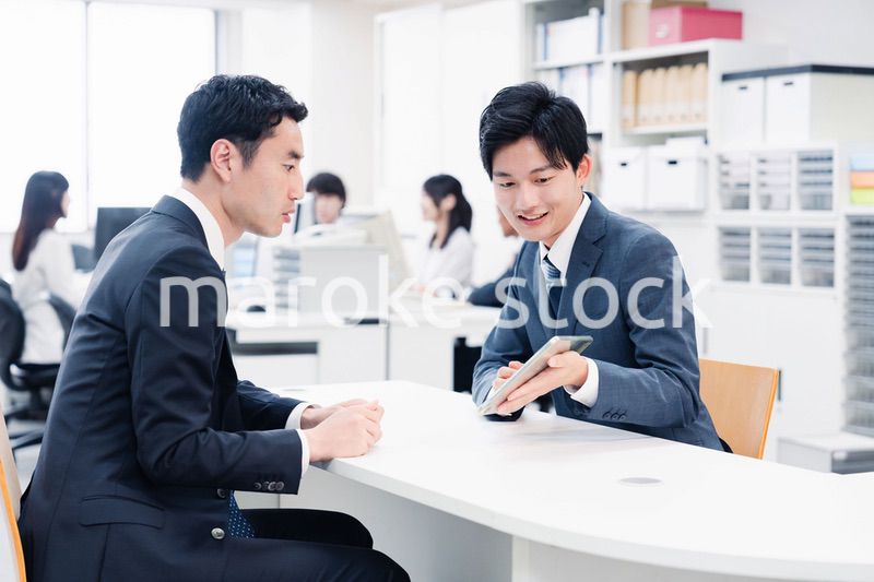 窓口でタブレットを用いて案内をする男性スタッフ