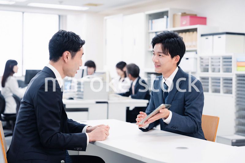 窓口でタブレットを用いて案内をする男性スタッフ