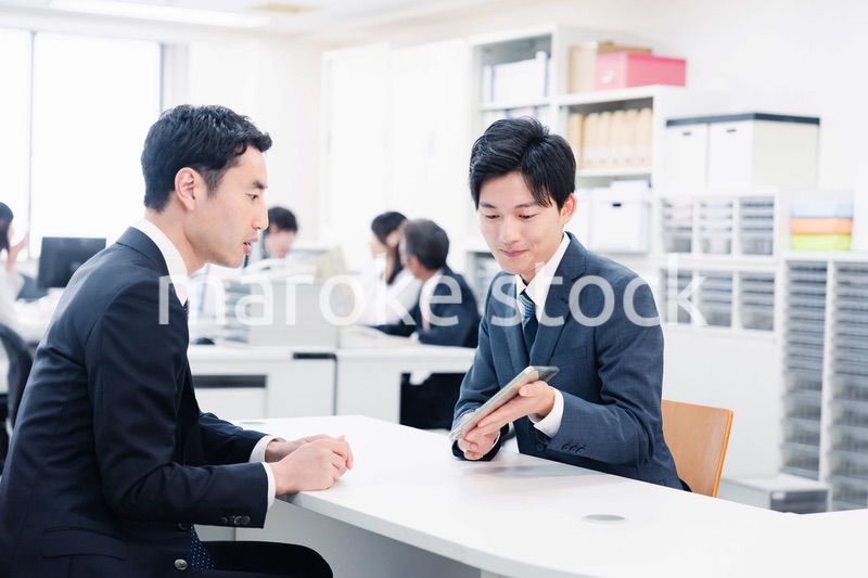 窓口でタブレットを用いて案内をする男性スタッフ