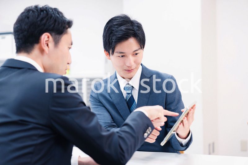 タブレット端末を使い窓口で説明をするビジネスマン