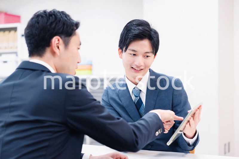 タブレット端末を使い窓口で説明をするビジネスマン