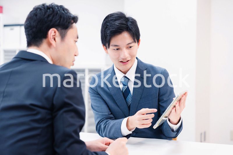 タブレット端末を使い窓口で説明をするビジネスマン