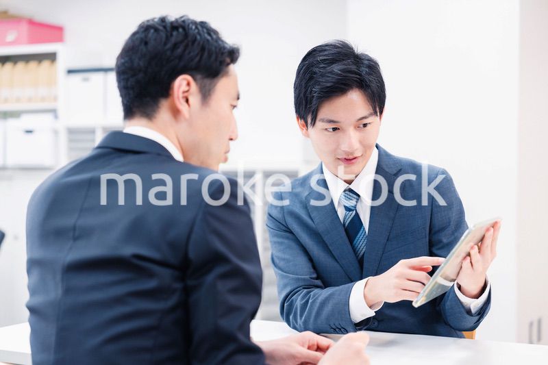 タブレット端末を使い窓口で説明をするビジネスマン