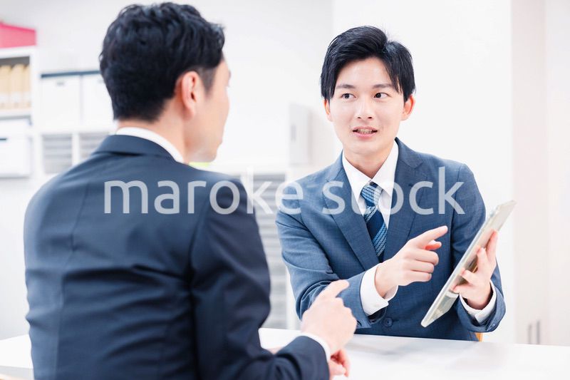 タブレット端末を使い窓口で説明をするビジネスマン