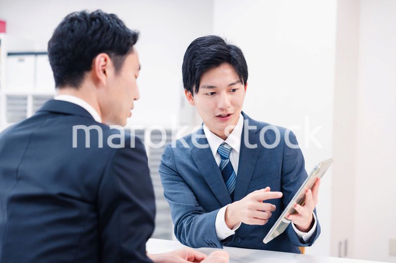 タブレット端末を使い窓口で説明をするビジネスマン