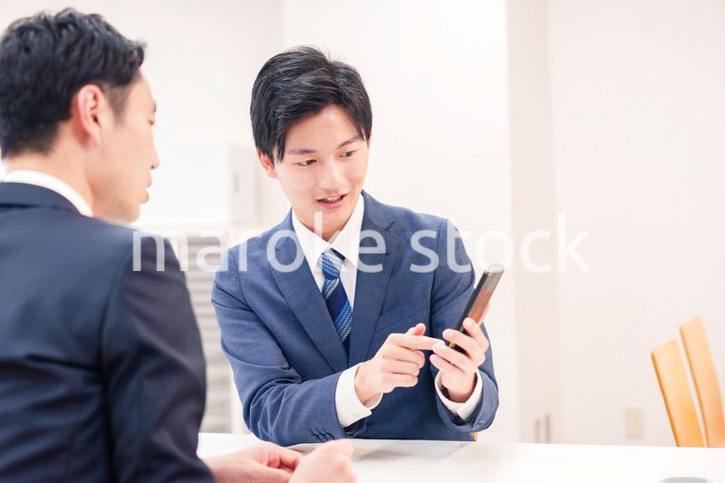 スマホを持って話をする二人のビジネスマン