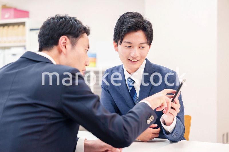スマホを持って話をする二人のビジネスマン