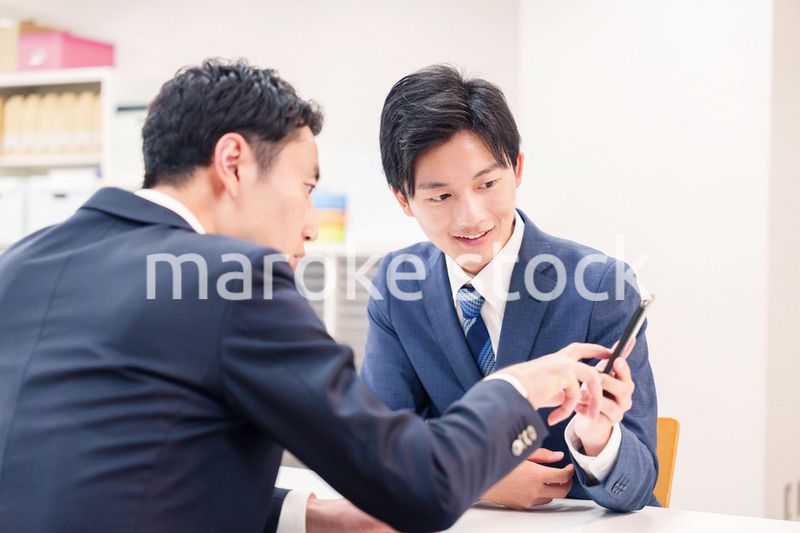 スマホを持って話をする二人のビジネスマン