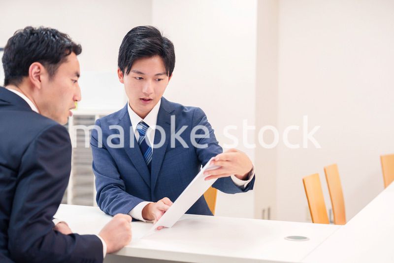 窓口で来客の対応をするビジネスマン